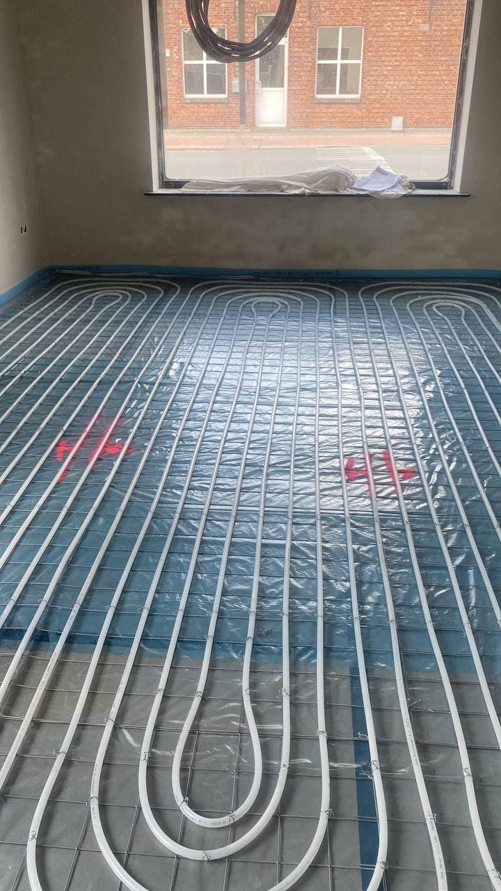 Vloerverwarmingsleidingen strak gelegd op een folie voor het storten van de dekvloer